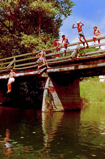 Kinder springen von Brcke ins Wasser