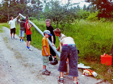 Durch ein ca. 5 Meter langes zusammengestecktes Abflussrohr (Baumarkt) müssen ca. 10 Tennisbälle gerollt oder Wasser aufgefangen werden.