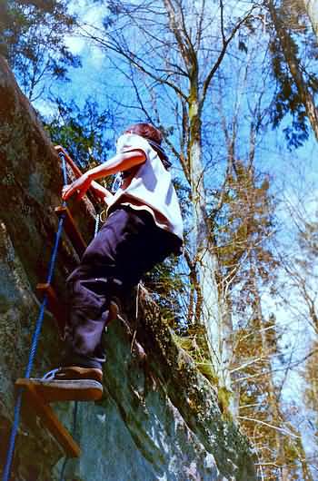 Outdoor-Abenteuer im Wald; hier an einer Strickleiter einen Felsen hoch klettern.