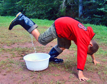 Mit dem Gummistiefel Wasser in eine Wanne gieen